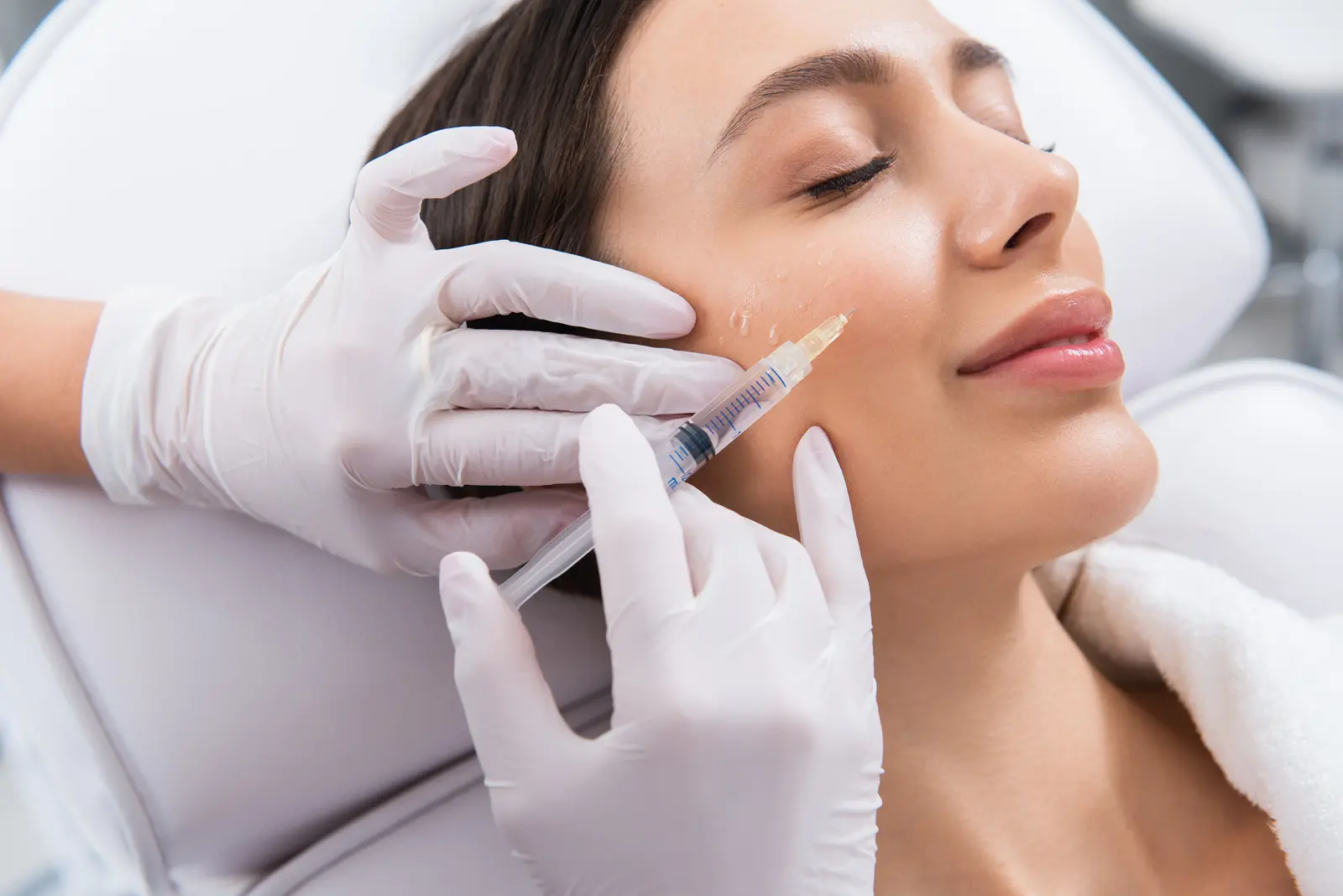 Woman receiving facial rejuvenation injection in cheek.